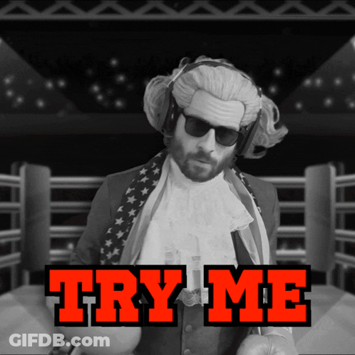 A Man In A Wig And Sunglasses Stands In A Boxing Ring With The Words Try Me Behind Him GIF
