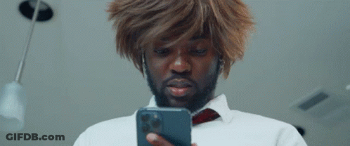 A Man In A Wig Is Looking At His Phone . GIF