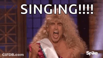 A Man In A Wig Is Singing While Wearing A Sash . GIF