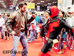A Man In A Wolverine Costume Stands Next To A Woman In A Deadpool Costume At A Convention GIF