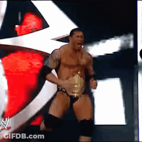 A Man In A Wrestling Outfit Is Holding A Wrestling Belt GIF