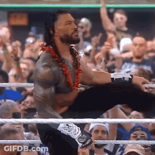 A Man In A Wrestling Ring Holds Another Man 'S Leg Up In The Air GIF