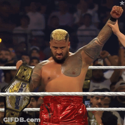 A Man In A Wrestling Ring Holds Up A Belt That Says World Heavyweight Champion GIF