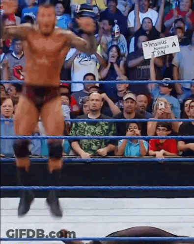 A Man In A Wrestling Ring Holds Up A Sign That Says ' Shawnus ' GIF