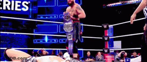 A Man In A Wrestling Ring Is Holding A Championship Belt . GIF
