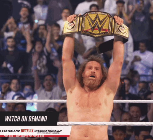 A Man In A Wrestling Ring Is Holding A WWE Championship Belt Above His Head GIF