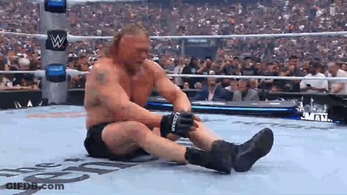 A Man In A Wrestling Ring Is Wearing A Pair Of Black Gloves With The Letter L On The Side GIF