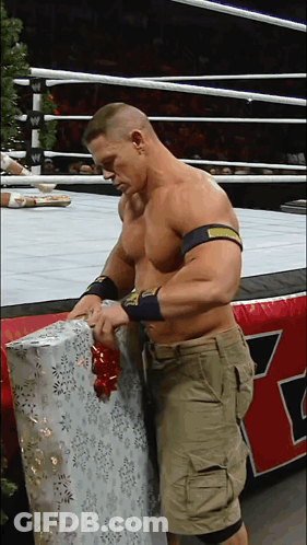 A Man In A Wrestling Ring Is Wrapping A Gift With A Bow GIF