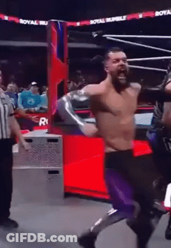 A Man In A Wrestling Ring With A Referee And A Sign That Says Royal Rumble On It GIF