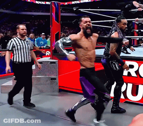 A Man In A Wrestling Ring With A Referee And A Sign That Says Royal Rumble On It GIF