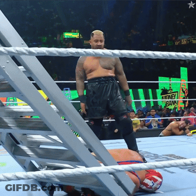 A Man In A Wrestling Ring With A Sign That Says Money Bank In The Background GIF
