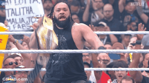 A Man In A Wrestling Ring With A Sign That Says ' Talitha ' On It GIF