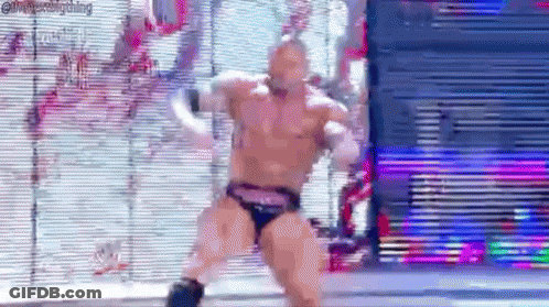 A Man In A Wrestling Trunks Is Dancing In Front Of A Screen . GIF