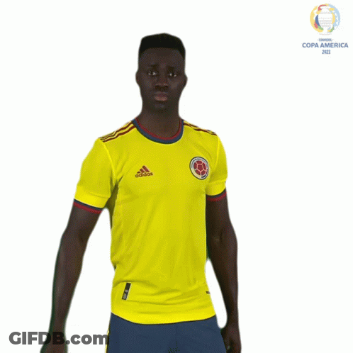 A Man In A Yellow Adidas Shirt Stands In Front Of A Copa America Logo GIF