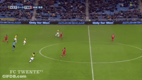 A Man In A Yellow And Black Striped Shirt Is Jumping In The Air In Front Of A Large D GIF
