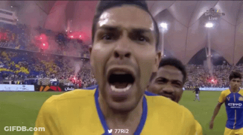A Man In A Yellow And Blue Jersey Is Screaming At The Camera GIF