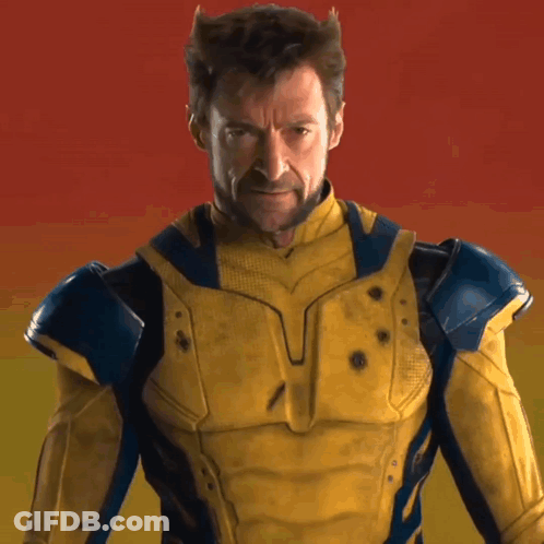 A Man In A Yellow And Blue Superhero Costume Looks At The Camera GIF