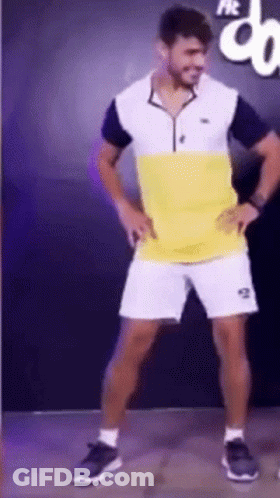 A Man In A Yellow And White Shirt And Shorts Is Dancing GIF