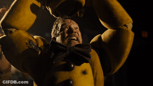 A Man In A Yellow Costume With A Bow Tie Is Screaming In The Dark GIF