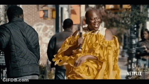A Man In A Yellow Dress Is Holding A Microphone And Smiling . GIF