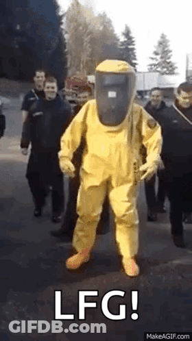 A Man In A Yellow Hazmat Suit Is Standing In Front Of A Group Of People . GIF
