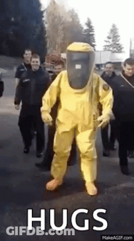 A Man In A Yellow Hazmat Suit Is Walking Down A Street . GIF