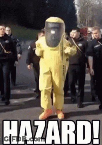 A Man In A Yellow Hazmat Suit Is Walking Down A Street Surrounded By Police Officers .. GIF