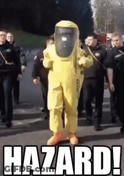 A Man In A Yellow Hazmat Suit Is Walking Down A Street Surrounded By Police Officers .. GIF