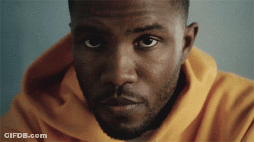 A Man In A Yellow Hoodie Looks At The Camera GIF