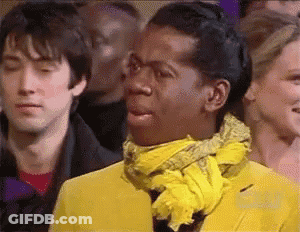 A Man In A Yellow Jacket And Scarf Is Making A Funny Face . GIF