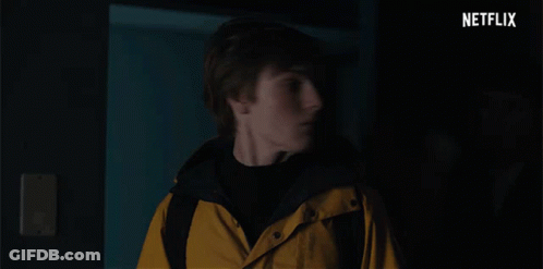 A Man In A Yellow Jacket Is Being Held By Another Man In A Dark Room With Netflix Written In The Corner GIF