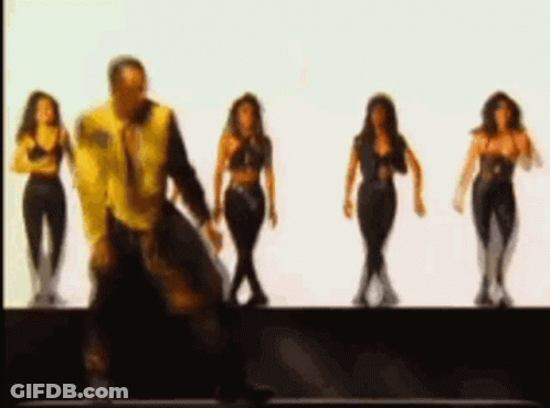 A Man In A Yellow Jacket Is Dancing With Three Women In Black Clothes . GIF