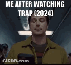 A Man In A Yellow Jacket Is Holding A Cell Phone In His Hand . GIF
