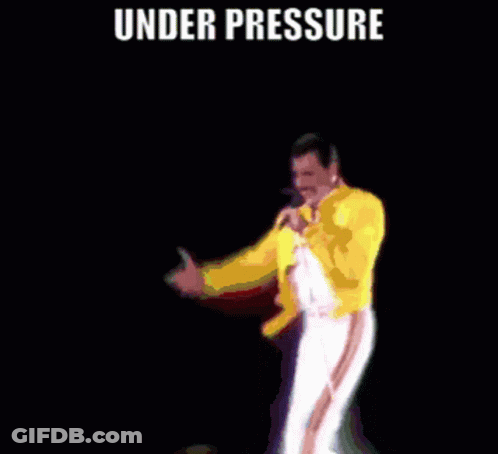 A Man In A Yellow Jacket Is Singing Into A Microphone Under The Words Under Pressure GIF