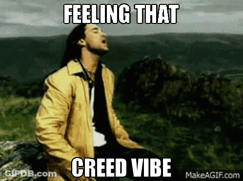 A Man In A Yellow Jacket Is Sitting On A Rock With The Words " Feeling That Creed Vibe " Written Above Him GIF