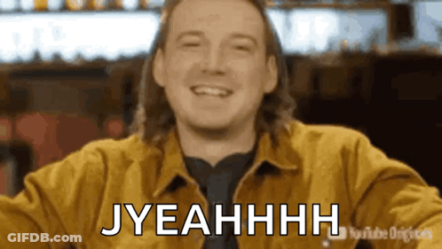 A Man In A Yellow Jacket Is Smiling And Says Jyeahhhh . GIF