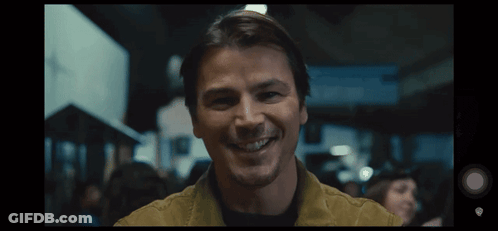 A Man In A Yellow Jacket Is Smiling In A Crowd GIF
