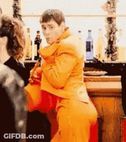 A Man In A Yellow Jacket Is Standing In Front Of A Bar GIF