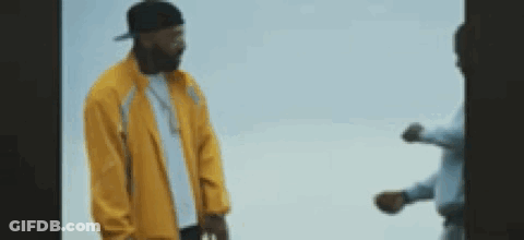 A Man In A Yellow Jacket Is Standing Next To Another Man In A Blue Shirt . GIF