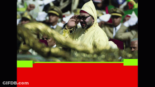 A Man In A Yellow Jacket Salutes In Front Of A Crowd Of People GIF