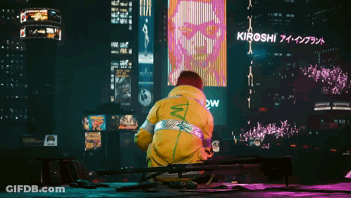A Man In A Yellow Jacket Stands In Front Of A Large Billboard That Says Kiroshi GIF