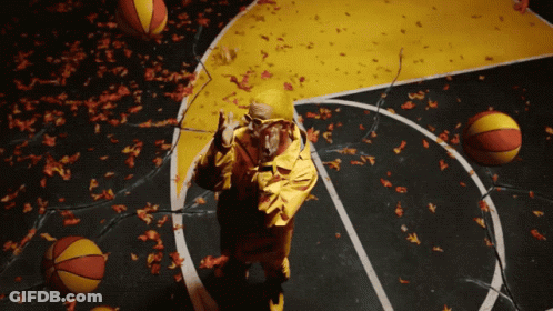 A Man In A Yellow Jacket Stands On A Basketball Court Surrounded By Basketballs And Leaves GIF