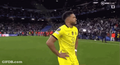 A Man In A Yellow Jersey Is Standing On A Soccer Field . GIF