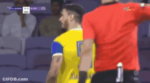 A Man In A Yellow Jersey With The Number 9 On It Stands Next To A Man In A Red Shirt GIF