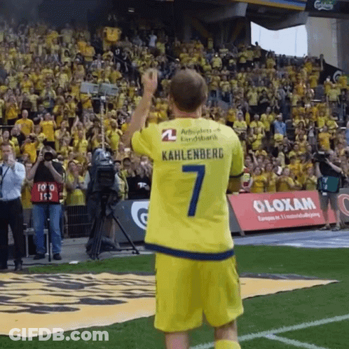 A Man In A Yellow Kahlenberg Jersey Stands On A Field GIF