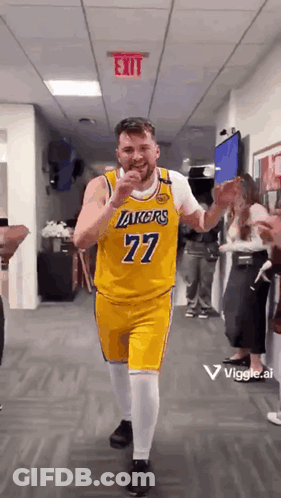 A Man In A Yellow Lakers Jersey Is Dancing In A Hallway . GIF