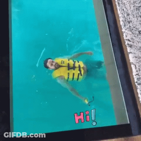 A Man In A Yellow Life Jacket Is Swimming In A Pool With The Word Hi On The Screen . GIF