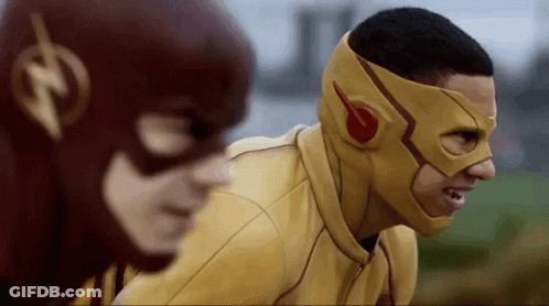 A Man In A Yellow Mask Is Standing Next To Another Man In A Red Mask . GIF