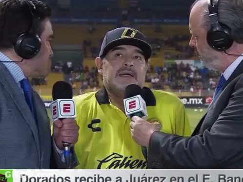 A Man In A Yellow Palien Shirt Is Being Interviewed GIF