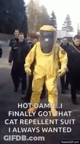 A Man In A Yellow Protective Suit Is Walking Down A Street With A Group Of People . GIF